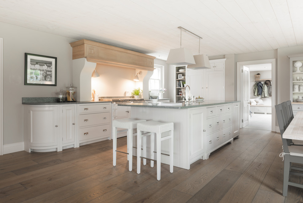 Traditional l-shaped kitchen/diner in Belfast with recessed-panel cabinets, white cabinets, white appliances, dark hardwood flooring, an island, brown floors and grey worktops.