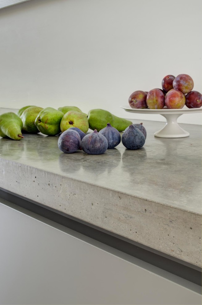 Immagine di un'ampia cucina minimal con lavello integrato, ante lisce, ante bianche, top in cemento, pavimento in cementine, penisola, pavimento grigio e top grigio