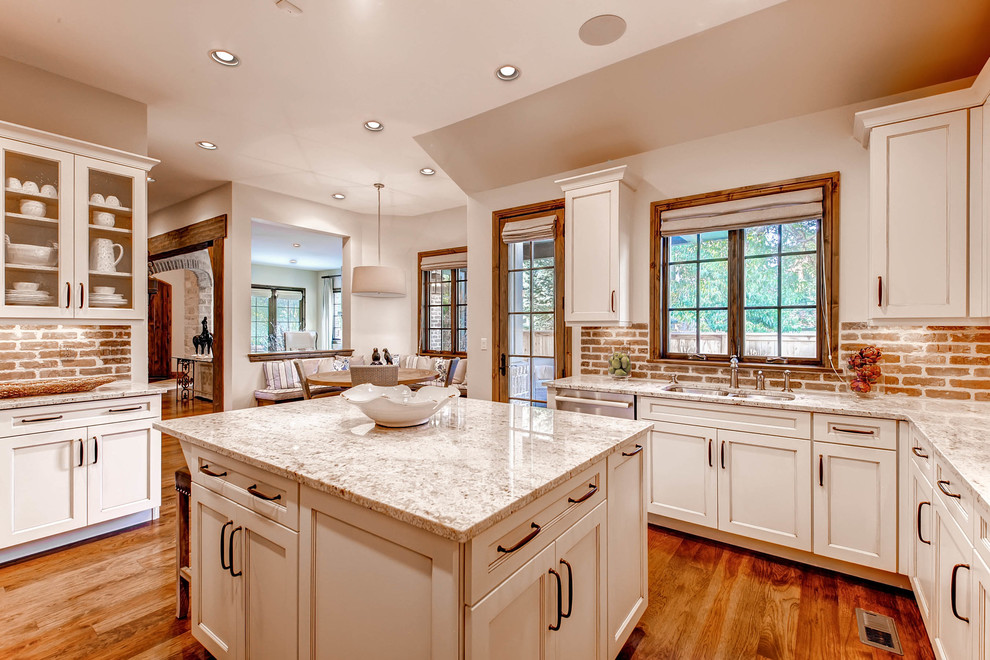 Example of a large transitional u-shaped medium tone wood floor open concept kitchen design in Denver with an undermount sink, shaker cabinets, white cabinets, granite countertops, brown backsplash, stainless steel appliances and an island