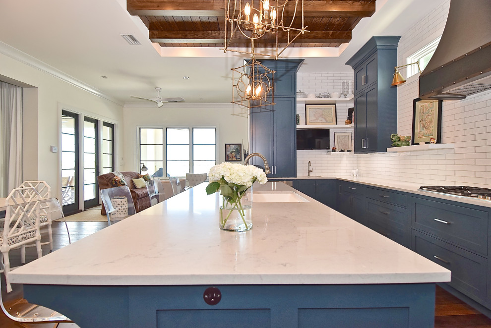 Inspiration for a traditional u-shaped kitchen/diner in Tampa with a submerged sink, shaker cabinets, blue cabinets, engineered stone countertops, white splashback, ceramic splashback, integrated appliances, medium hardwood flooring, an island, brown floors and white worktops.
