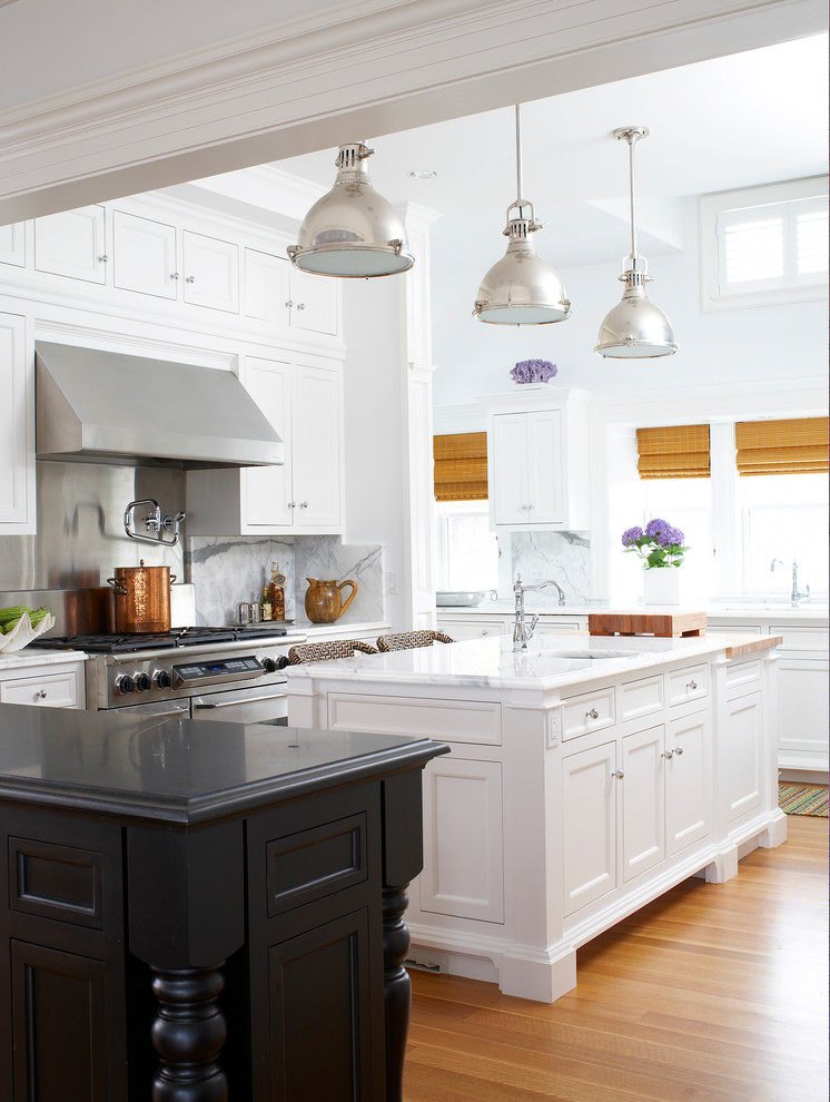 Example of an ornate u-shaped medium tone wood floor eat-in kitchen design in Miami with an undermount sink, recessed-panel cabinets, white cabinets, marble countertops, white backsplash, stone slab backsplash and stainless steel appliances