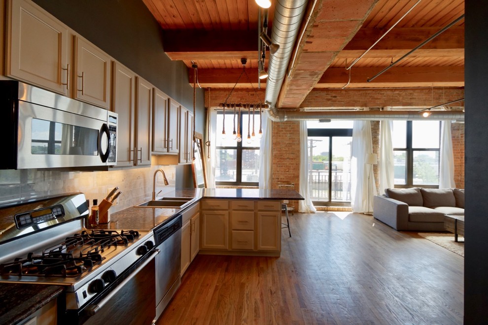 Inspiration for a medium sized industrial l-shaped open plan kitchen in Chicago with a double-bowl sink, recessed-panel cabinets, white cabinets, granite worktops, white splashback, stainless steel appliances, medium hardwood flooring, a breakfast bar and brown floors.