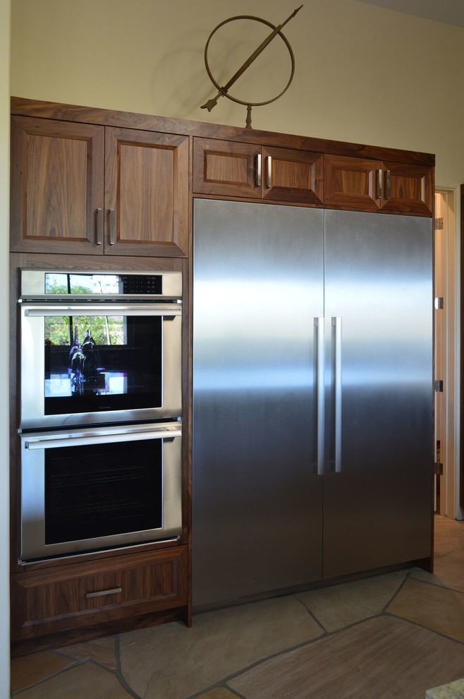 Eat-in kitchen - large contemporary u-shaped beige floor and travertine floor eat-in kitchen idea in Phoenix with recessed-panel cabinets, medium tone wood cabinets, beige backsplash, stainless steel appliances, an island, a farmhouse sink, granite countertops and metal backsplash