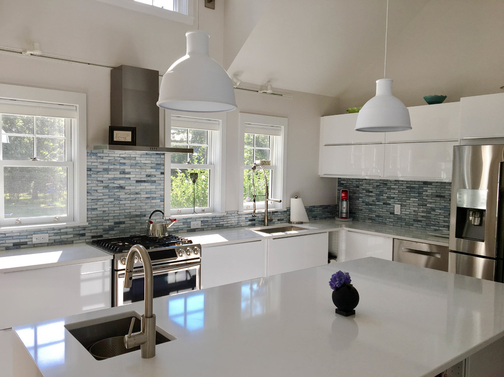 Photo of a medium sized modern l-shaped kitchen/diner in Other with a submerged sink, flat-panel cabinets, white cabinets, glass tiled splashback, stainless steel appliances, an island, medium hardwood flooring, brown floors, blue splashback and engineered stone countertops.
