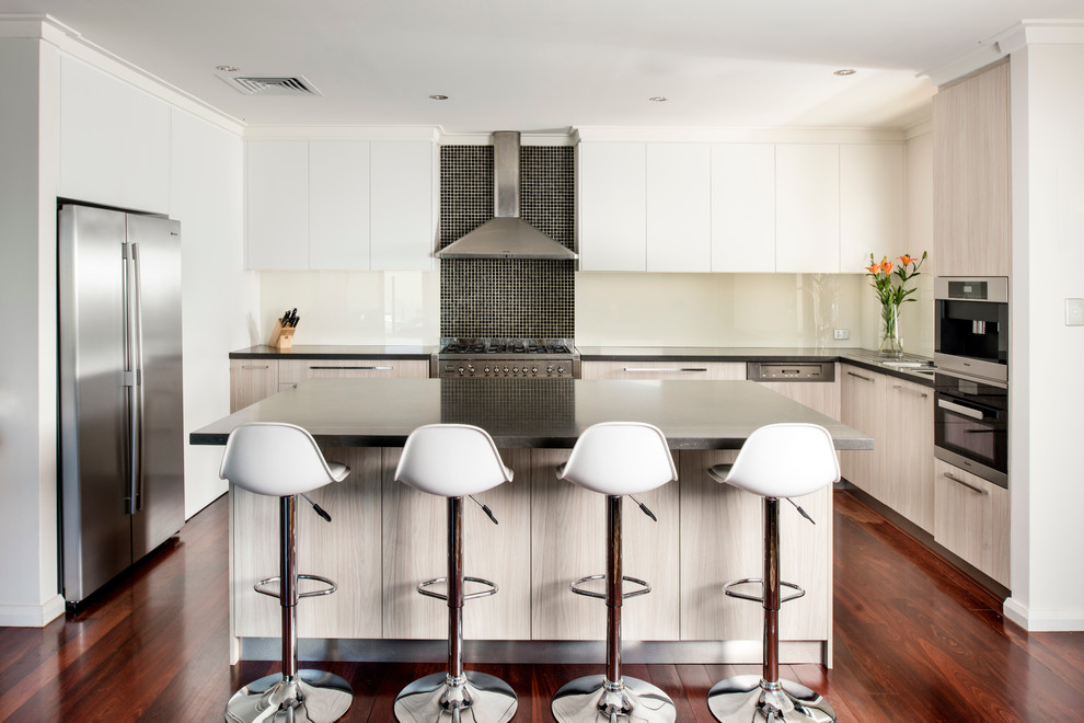 Trendy u-shaped dark wood floor kitchen photo in Perth with flat-panel cabinets, light wood cabinets, black backsplash, mosaic tile backsplash, stainless steel appliances and an island