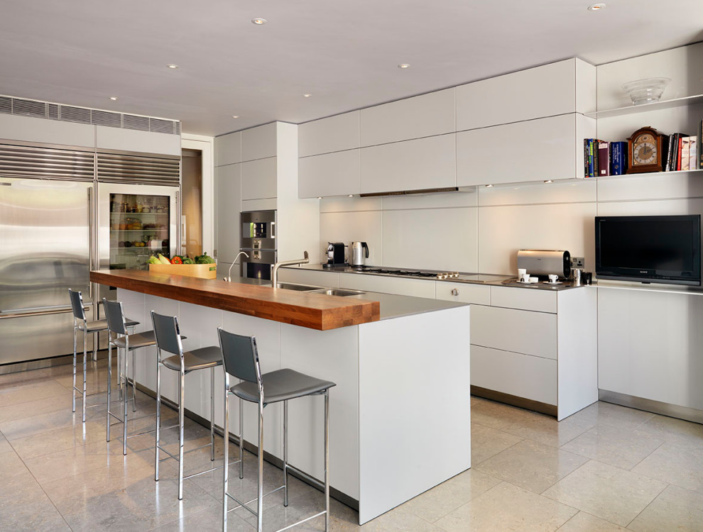 Design ideas for a contemporary kitchen in London with an integrated sink, flat-panel cabinets, grey cabinets, stainless steel worktops, beige splashback, stainless steel appliances, an island and beige floors.
