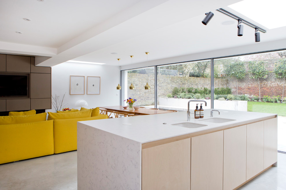 This is an example of a medium sized contemporary u-shaped open plan kitchen in London with a built-in sink, flat-panel cabinets, light wood cabinets, marble worktops, beige splashback, porcelain splashback, stainless steel appliances, concrete flooring, an island, grey floors and grey worktops.
