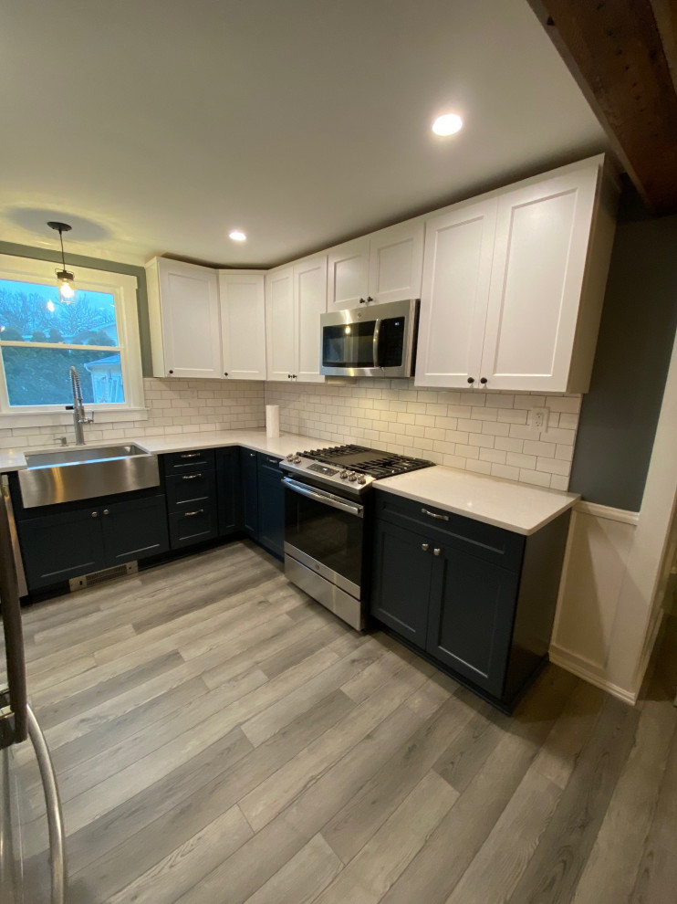 Mid-sized transitional l-shaped gray floor enclosed kitchen photo in Providence with a farmhouse sink, flat-panel cabinets, blue cabinets, quartz countertops, white backsplash, stainless steel appliances, no island and white countertops