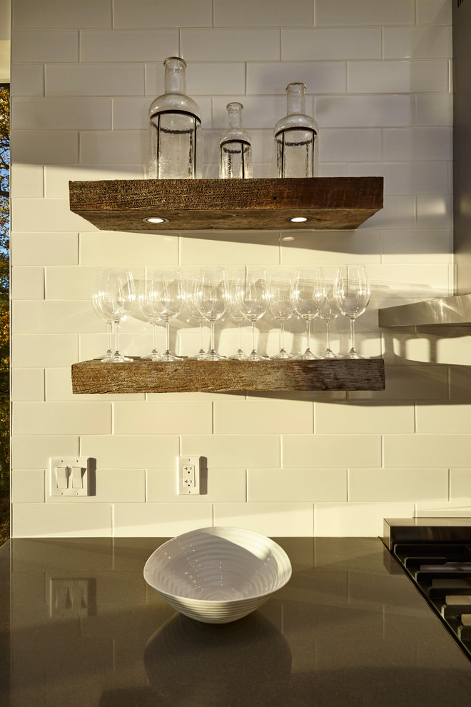 Photo of a medium sized traditional l-shaped kitchen in Toronto with a double-bowl sink, white cabinets, white splashback, stainless steel appliances, light hardwood flooring, an island and brown floors.