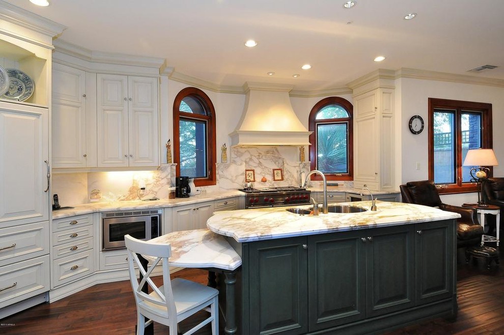 Exempel på ett stort klassiskt kök, med luckor med upphöjd panel, vita skåp, integrerade vitvaror, en köksö, en dubbel diskho, bänkskiva i onyx, stänkskydd i sten och mellanmörkt trägolv
