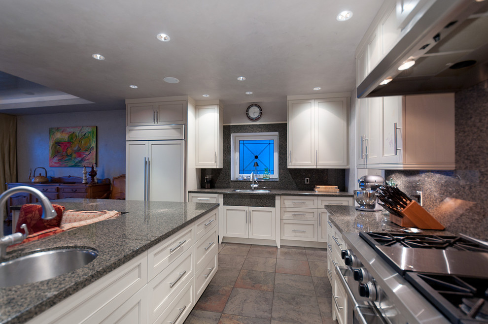 Foto på ett mellanstort funkis kök, med skåp i shakerstil, vita skåp, granitbänkskiva, brunt stänkskydd, stänkskydd i sten, rostfria vitvaror, klinkergolv i keramik och en köksö