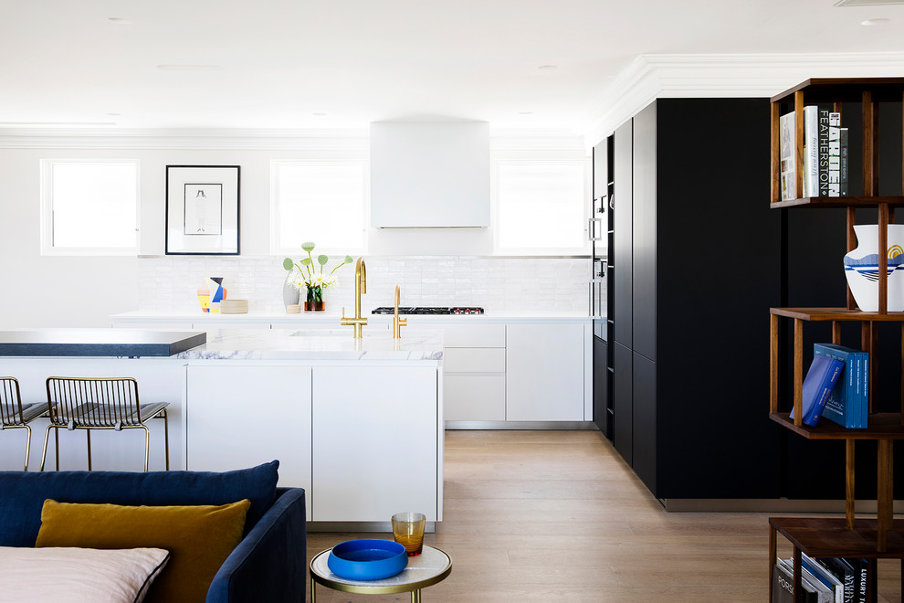 Offene Moderne Küche in L-Form mit Unterbauwaschbecken, flächenbündigen Schrankfronten, weißen Schränken, Küchenrückwand in Weiß, braunem Holzboden, Kücheninsel, braunem Boden und weißer Arbeitsplatte in Sydney