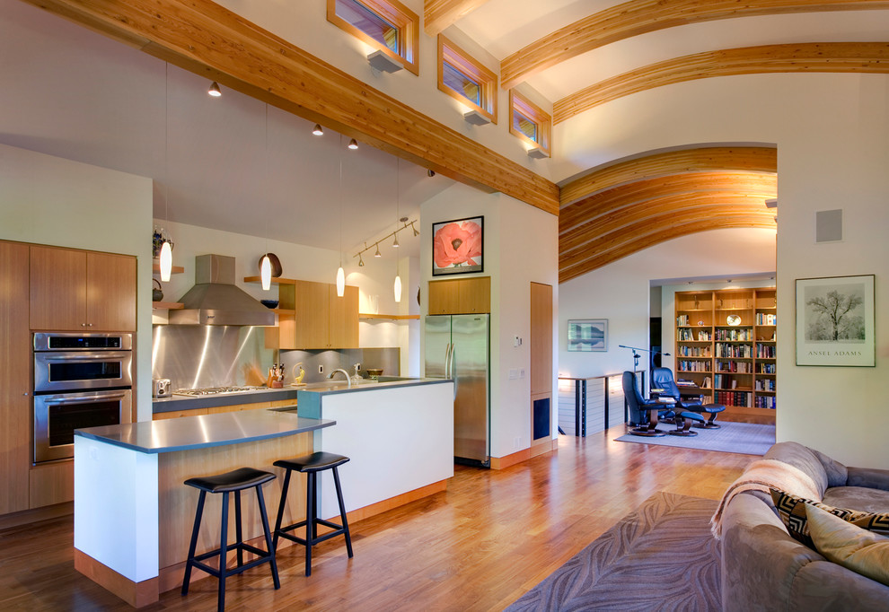 Zweizeilige Moderne Küche mit flächenbündigen Schrankfronten, hellbraunen Holzschränken, Rückwand aus Metallfliesen und Küchengeräten aus Edelstahl in Seattle