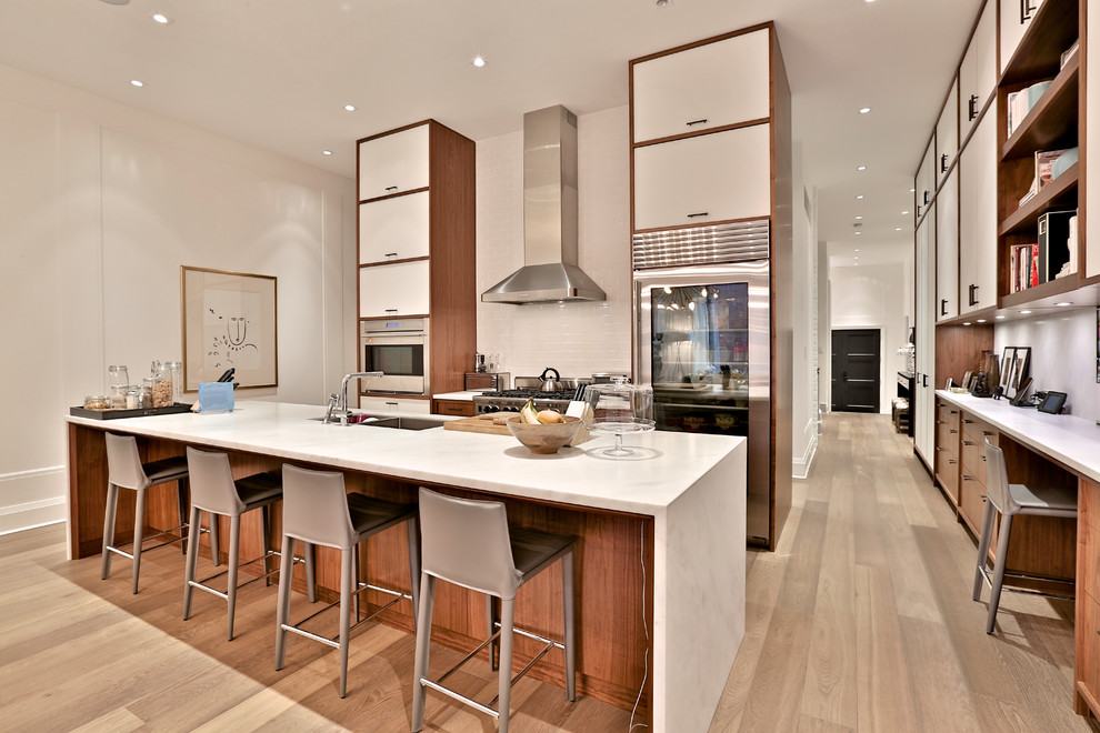 Open concept kitchen - huge transitional single-wall medium tone wood floor open concept kitchen idea in Toronto with a double-bowl sink, recessed-panel cabinets, beige cabinets, marble countertops, white backsplash, subway tile backsplash, stainless steel appliances and an island
