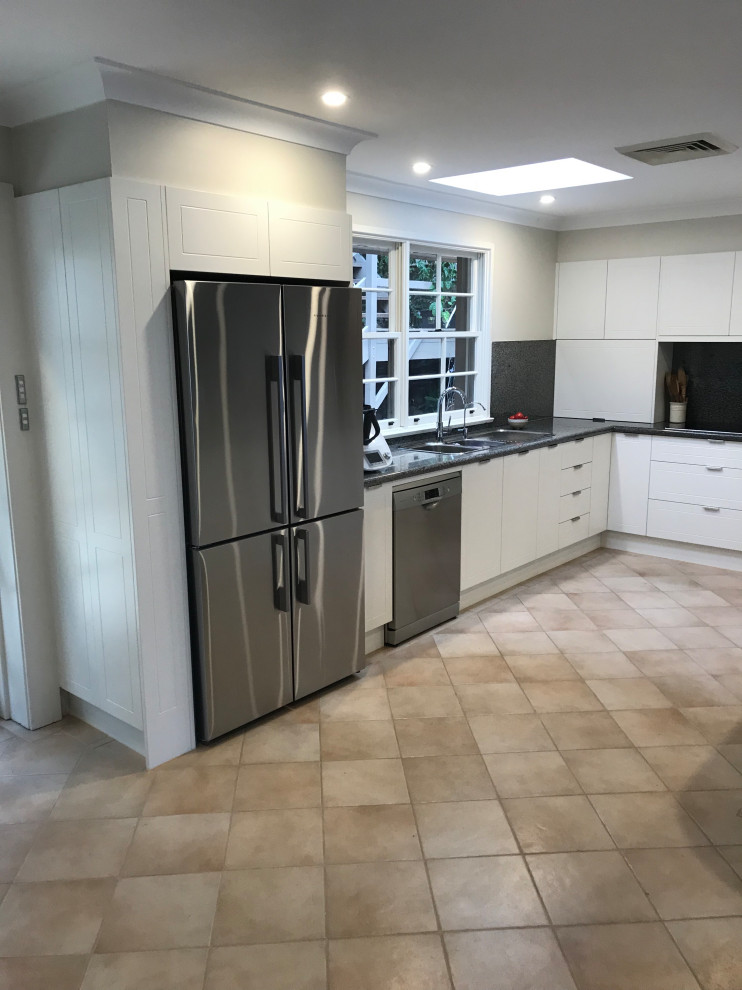 Trendy u-shaped kitchen pantry photo in Sydney with shaker cabinets, white cabinets, black backsplash, stainless steel appliances, a peninsula and black countertops