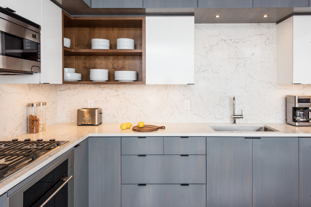 Modern inredning av ett litet vit vitt kök, med en undermonterad diskho, släta luckor, grå skåp, bänkskiva i kvarts, vitt stänkskydd, stänkskydd i sten och rostfria vitvaror