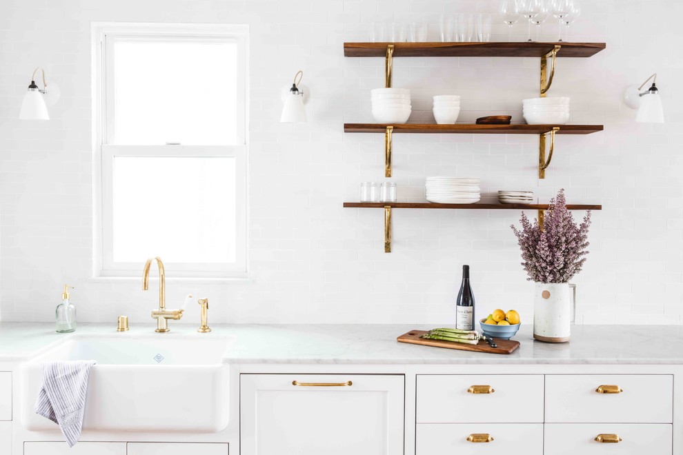 Eat-in kitchen - mid-sized transitional single-wall light wood floor eat-in kitchen idea in San Francisco with a farmhouse sink, flat-panel cabinets, white cabinets, marble countertops, white backsplash, ceramic backsplash, white appliances and an island