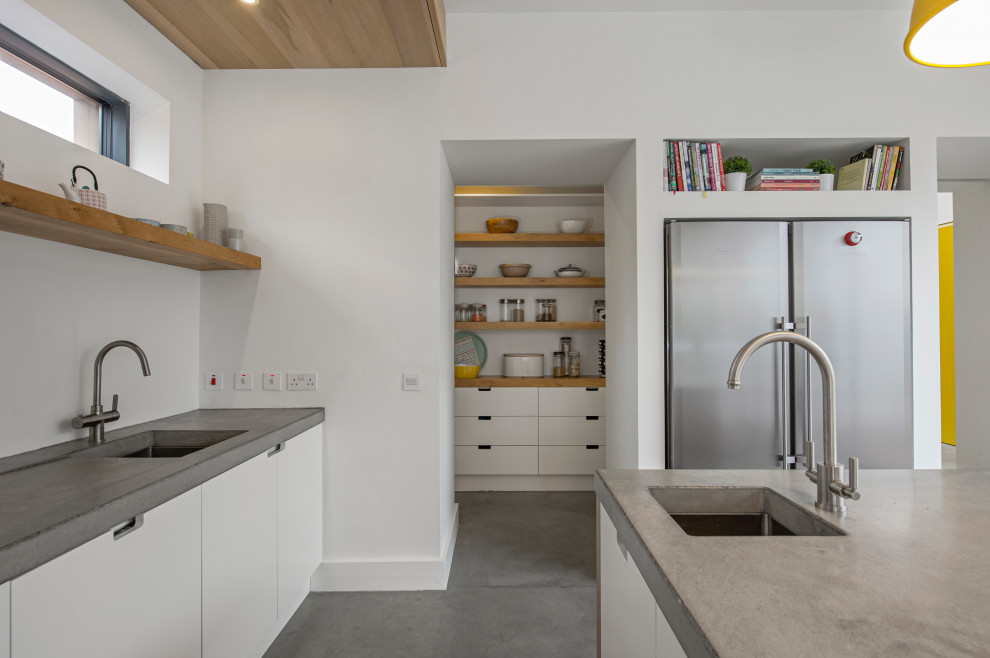 Photo of a medium sized contemporary open plan kitchen in Other with a built-in sink, flat-panel cabinets, white cabinets, concrete worktops, white splashback, stainless steel appliances, concrete flooring, an island, grey floors, grey worktops and a timber clad ceiling.