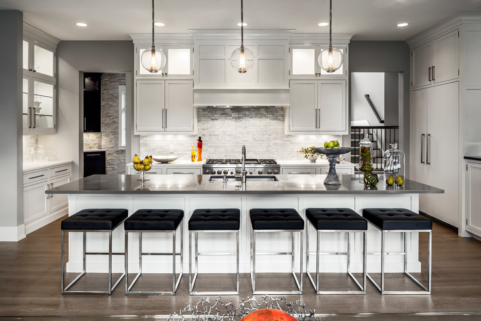 Inspiration for a large transitional u-shaped light wood floor eat-in kitchen remodel in Grand Rapids with recessed-panel cabinets, gray cabinets, quartzite countertops, beige backsplash, matchstick tile backsplash, stainless steel appliances and an island