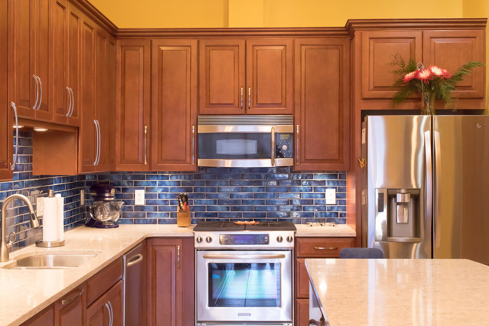 Bild på ett mellanstort vintage kök, med en undermonterad diskho, luckor med upphöjd panel, bruna skåp, bänkskiva i kvarts, blått stänkskydd, stänkskydd i porslinskakel, rostfria vitvaror, klinkergolv i keramik, en köksö och beiget golv
