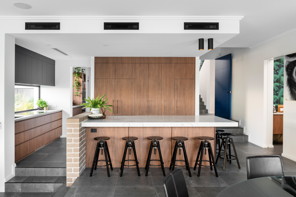 This is an example of a large contemporary l-shaped open plan kitchen in Perth with a submerged sink, flat-panel cabinets, medium wood cabinets, window splashback, integrated appliances, an island, grey floors and white worktops.