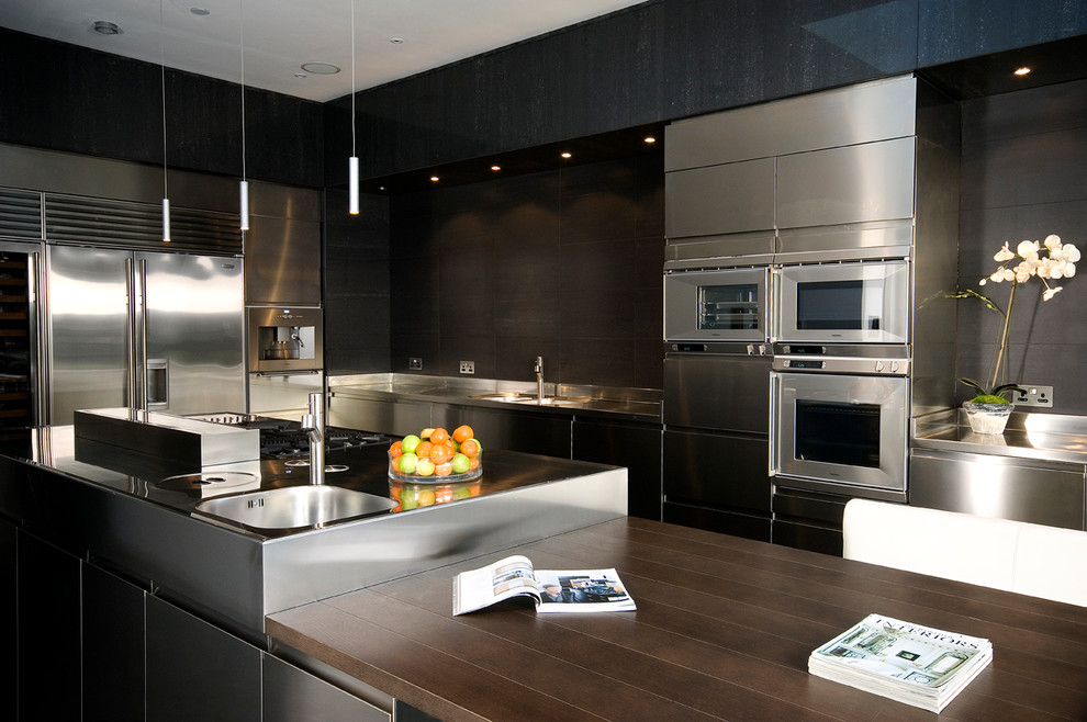 Design ideas for a contemporary galley kitchen in Other with an integrated sink, flat-panel cabinets, stainless steel cabinets, stainless steel worktops, black splashback and stainless steel appliances.
