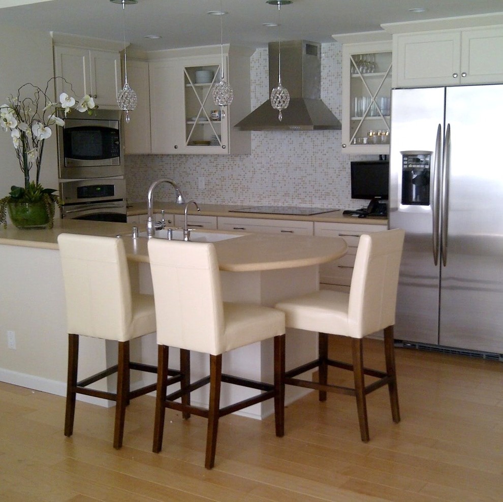 Example of a small eclectic u-shaped light wood floor open concept kitchen design in Los Angeles with a double-bowl sink, recessed-panel cabinets, white cabinets, solid surface countertops, white backsplash and stainless steel appliances