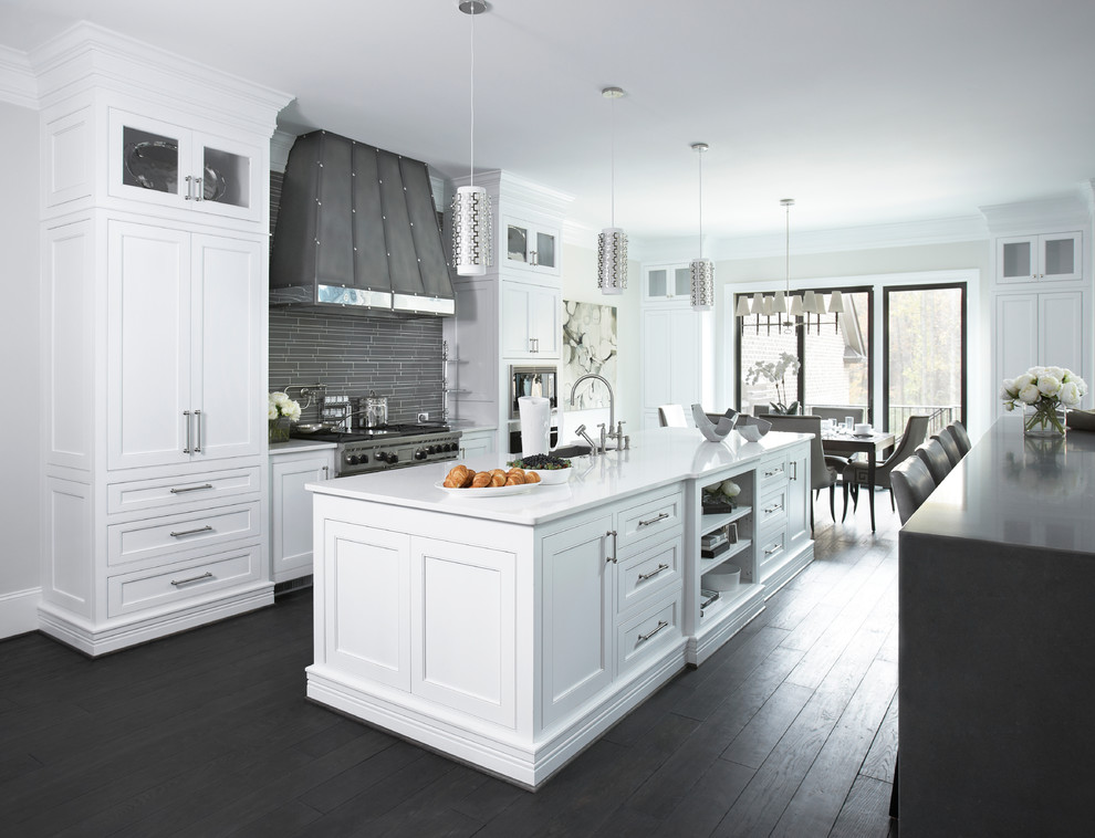 Large traditional grey and cream galley kitchen/diner in Other with recessed-panel cabinets, white cabinets, grey splashback, dark hardwood flooring, an island, glass tiled splashback, marble worktops and a submerged sink.