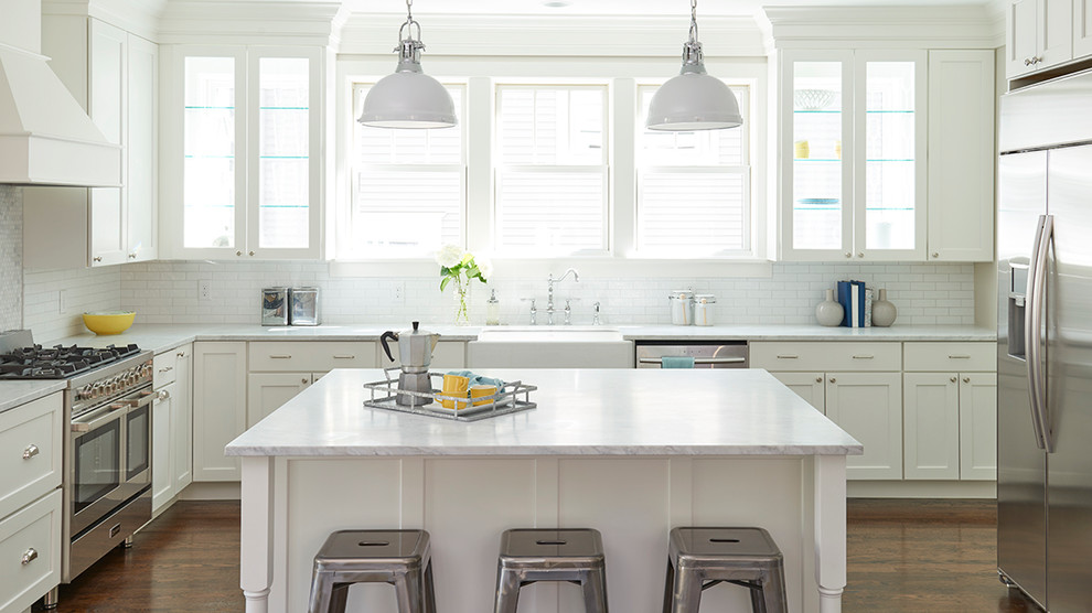 Example of a large transitional u-shaped dark wood floor eat-in kitchen design in Minneapolis with a farmhouse sink, recessed-panel cabinets, white cabinets, marble countertops, white backsplash, subway tile backsplash, stainless steel appliances and an island