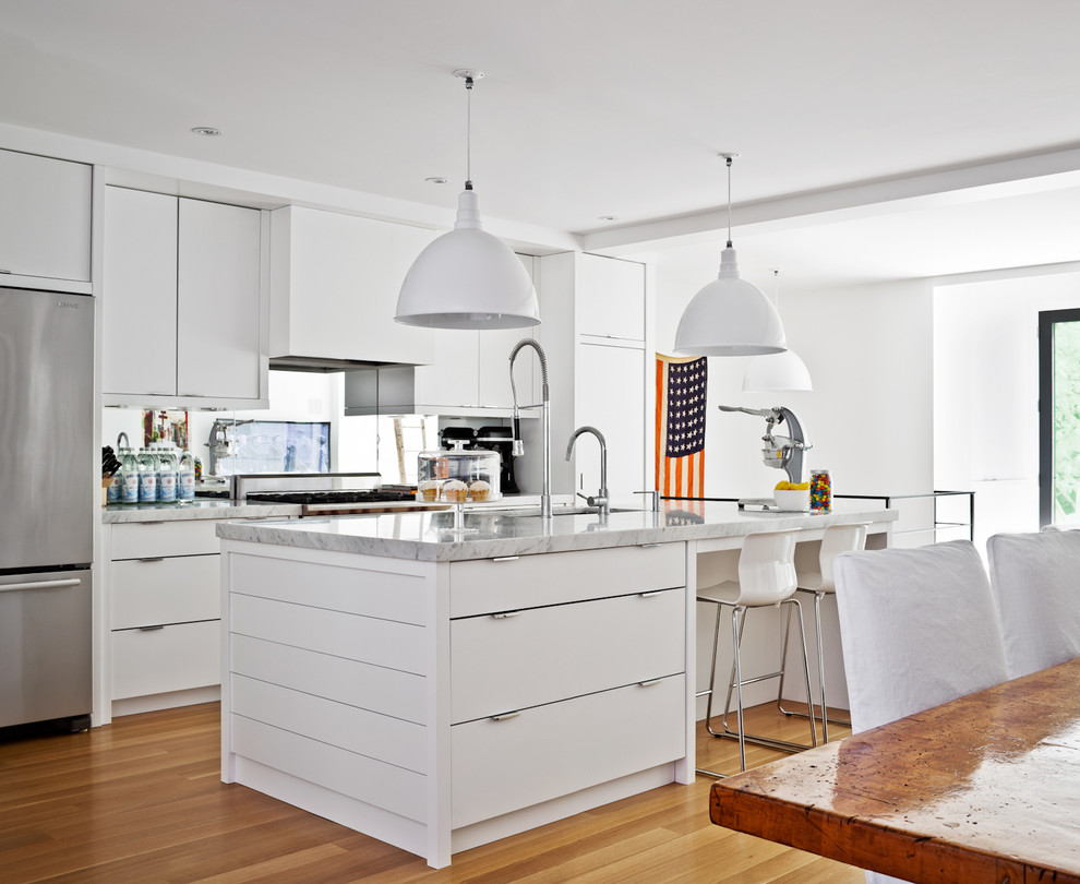 Zweizeilige Moderne Wohnküche mit Kücheninsel, weißen Schränken, Marmor-Arbeitsplatte, flächenbündigen Schrankfronten, Waschbecken, Küchengeräten aus Edelstahl und braunem Holzboden in Toronto