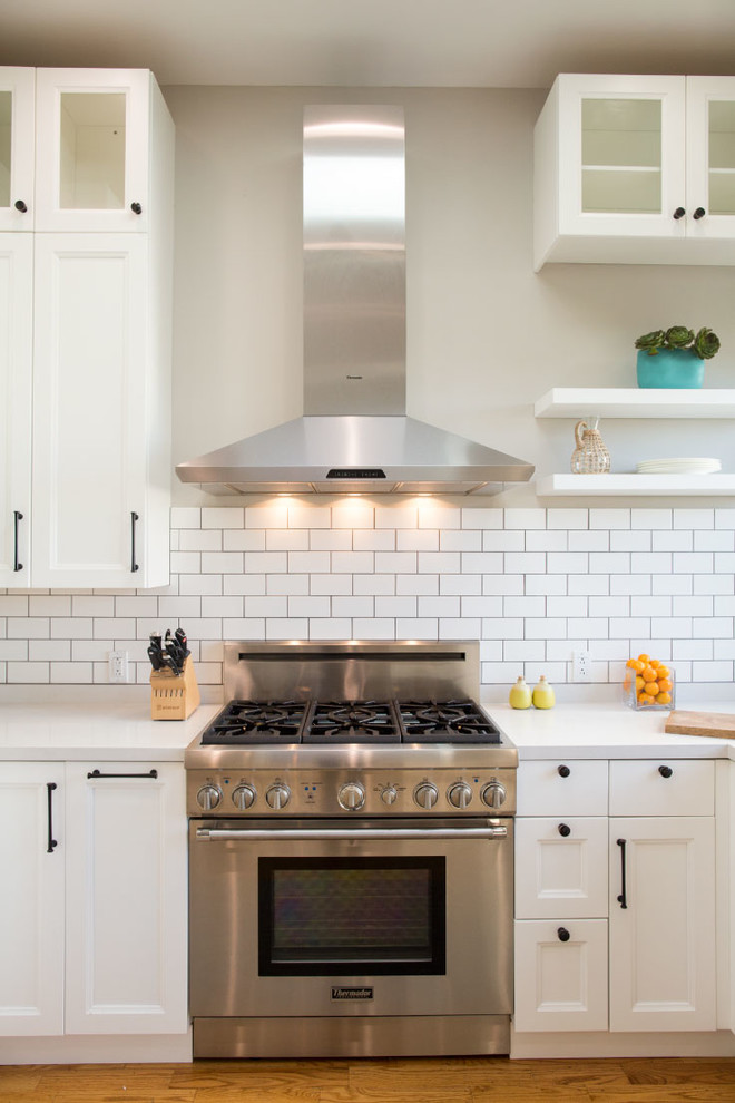 Example of a transitional u-shaped eat-in kitchen design in San Francisco with an undermount sink, beaded inset cabinets, white cabinets, quartz countertops, white backsplash, porcelain backsplash and stainless steel appliances