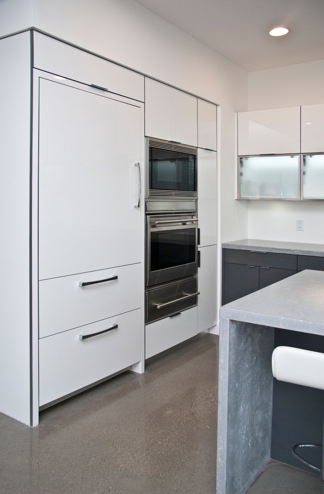 Exempel på ett litet modernt grå grått kök, med en undermonterad diskho, släta luckor, vita skåp, bänkskiva i kvarts, integrerade vitvaror, en köksö, grått golv och betonggolv