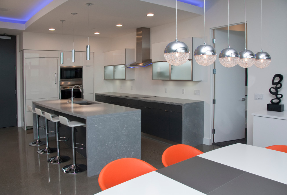 Example of a small trendy galley concrete floor and gray floor eat-in kitchen design in Grand Rapids with an undermount sink, flat-panel cabinets, white cabinets, quartz countertops, paneled appliances, an island and gray countertops