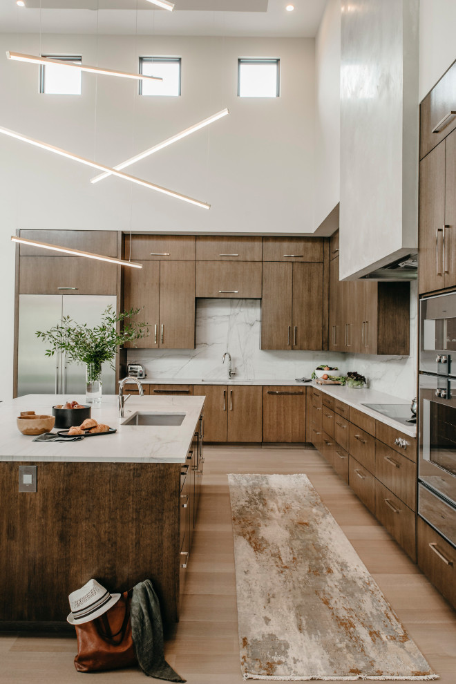 Design ideas for a large contemporary l-shaped kitchen in Austin with a submerged sink, flat-panel cabinets, medium wood cabinets, grey splashback, stainless steel appliances, an island, beige floors and grey worktops.