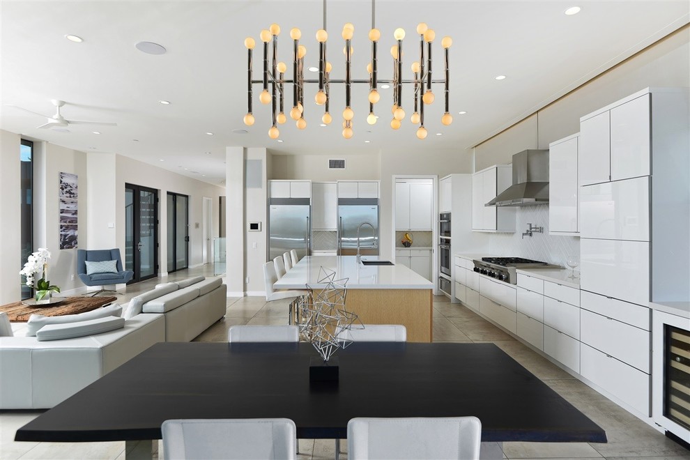 Photo of a large contemporary l-shaped open plan kitchen in San Diego with a submerged sink, flat-panel cabinets, white cabinets, engineered stone countertops, white splashback, glass tiled splashback, stainless steel appliances, ceramic flooring, an island and grey floors.