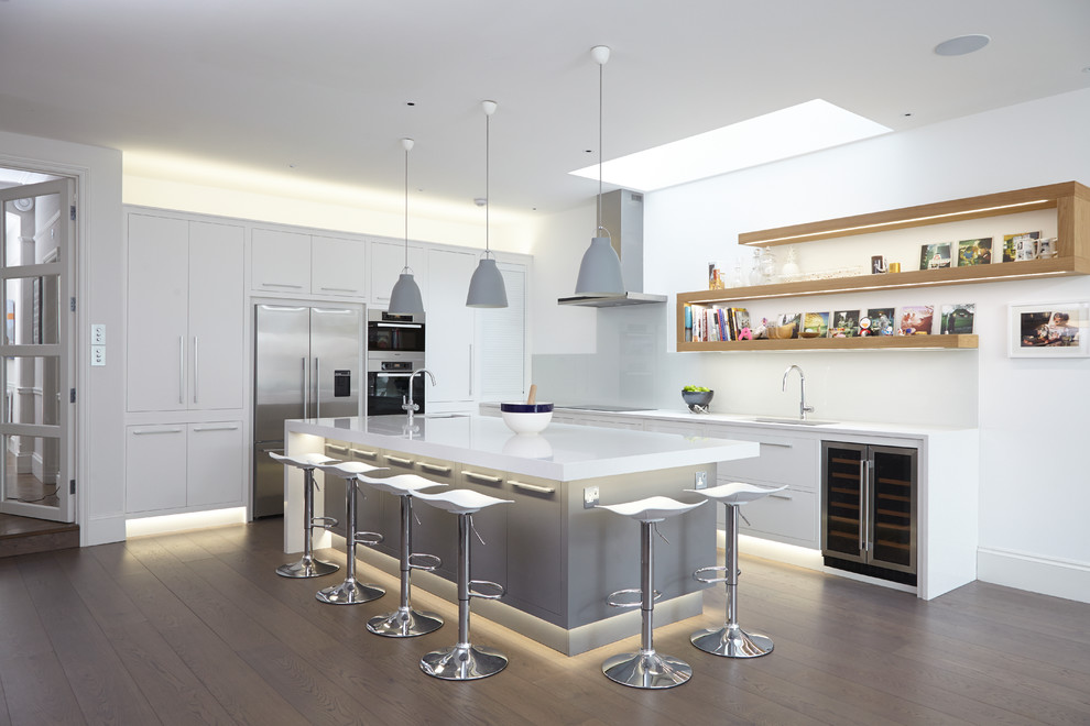 Kitchen - contemporary l-shaped medium tone wood floor kitchen idea in London with an undermount sink, flat-panel cabinets, white cabinets, white backsplash, glass sheet backsplash, stainless steel appliances and an island