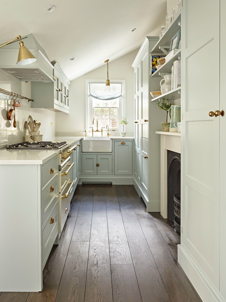 Small elegant l-shaped dark wood floor and brown floor enclosed kitchen photo in London with a farmhouse sink, shaker cabinets, blue cabinets, white appliances, white countertops, white backsplash and no island
