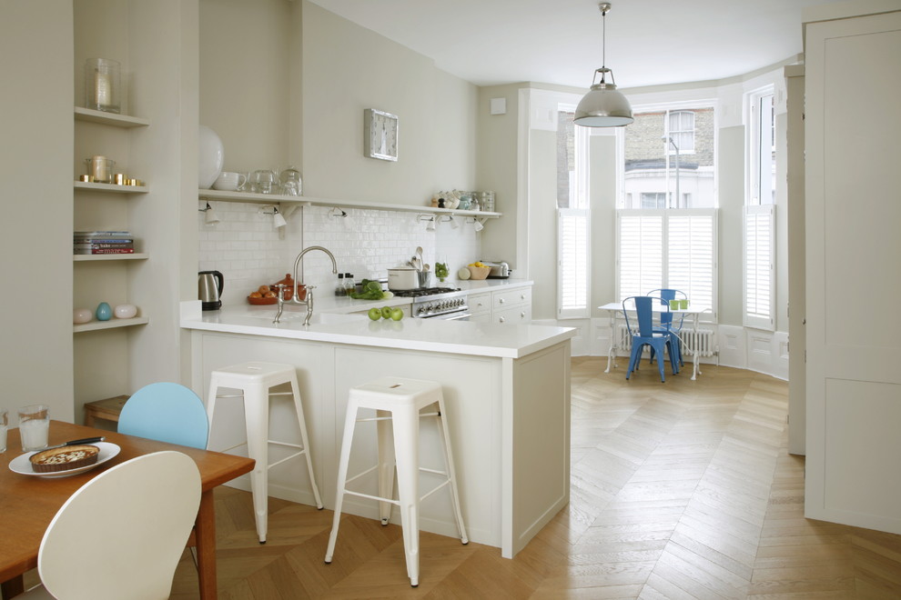 Inspiration for a mid-sized timeless l-shaped medium tone wood floor eat-in kitchen remodel in London with an undermount sink, white cabinets, solid surface countertops, white backsplash, subway tile backsplash, stainless steel appliances, a peninsula and open cabinets