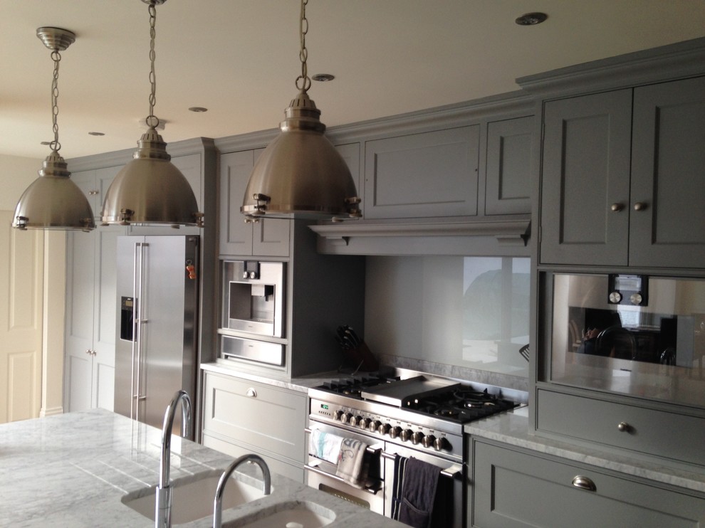 Example of a mid-sized classic single-wall medium tone wood floor eat-in kitchen design in London with an undermount sink, shaker cabinets, gray cabinets, marble countertops, gray backsplash, glass sheet backsplash, stainless steel appliances and an island