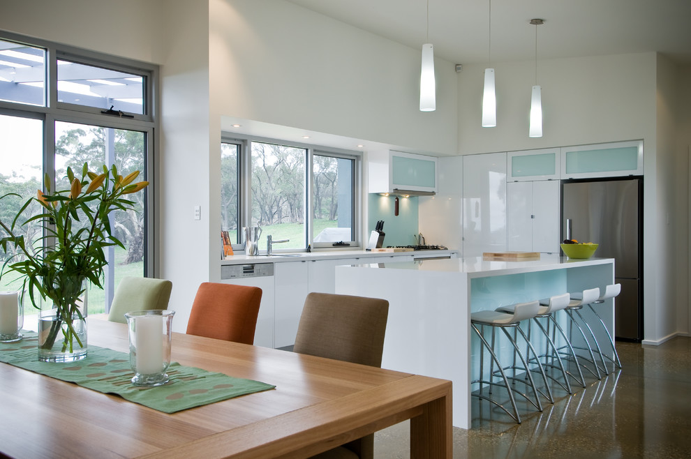 Example of a mid-sized trendy galley kitchen design in Adelaide with flat-panel cabinets, white cabinets and an island