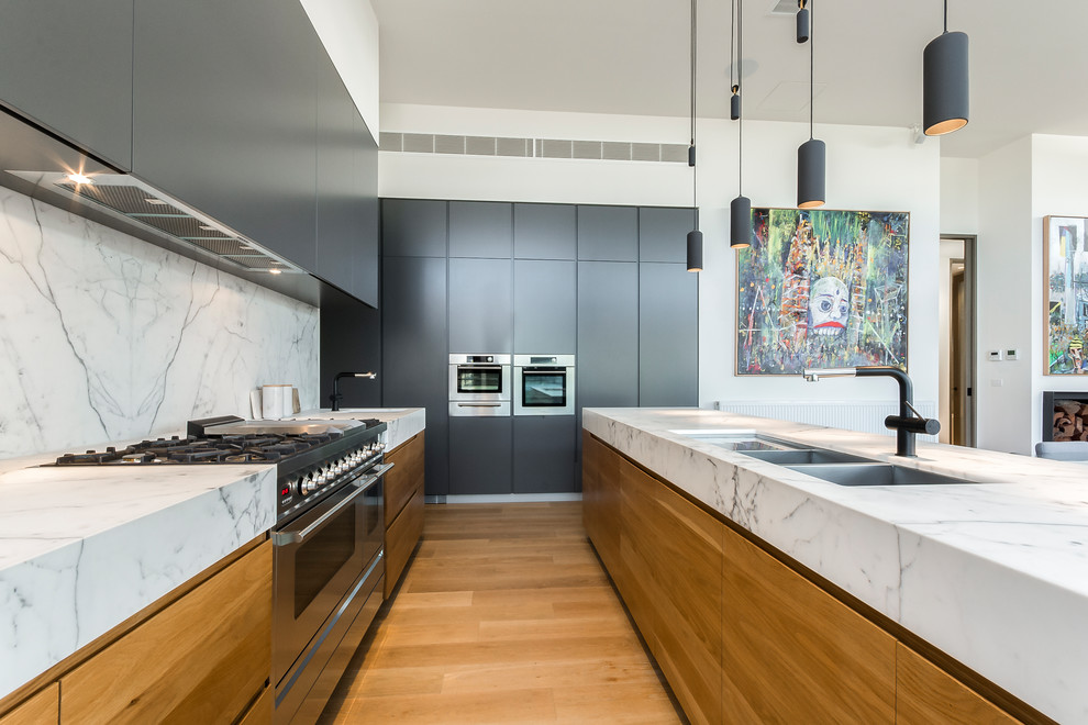 Immagine di una cucina minimal con ante lisce, lavello sottopiano, ante in legno scuro, paraspruzzi grigio, elettrodomestici in acciaio inossidabile, pavimento in legno massello medio e pavimento beige