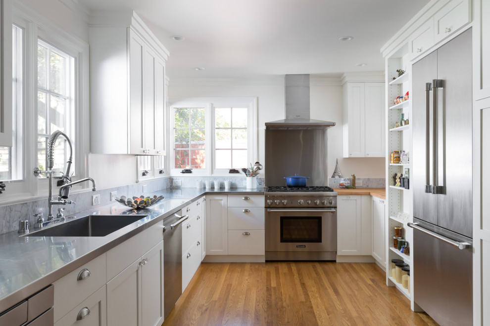 Photo of a traditional u-shaped kitchen in San Francisco with an integrated sink, shaker cabinets, white cabinets, stainless steel worktops, stainless steel appliances, medium hardwood flooring, no island, brown floors and grey worktops.