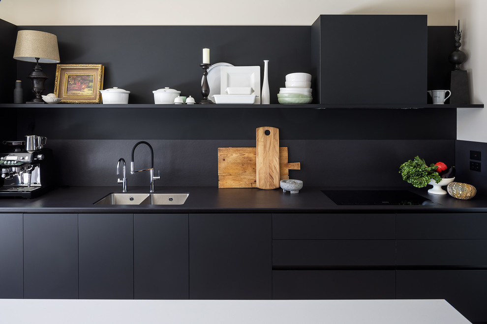Foto di una grande cucina minimal con ante in legno bruno, top in superficie solida, paraspruzzi nero, elettrodomestici neri, parquet chiaro e top bianco