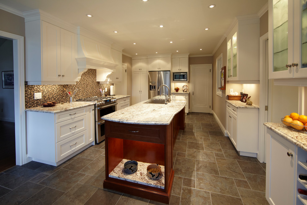 This is an example of a traditional u-shaped kitchen/diner in Toronto with a submerged sink, recessed-panel cabinets, medium wood cabinets, granite worktops, multi-coloured splashback, glass tiled splashback and stainless steel appliances.