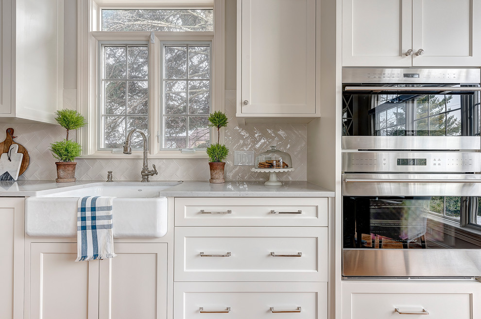 Exempel på ett mellanstort kök, med en rustik diskho, skåp i shakerstil, vita skåp, bänkskiva i kvarts, vitt stänkskydd, stänkskydd i keramik, integrerade vitvaror, ljust trägolv och en köksö