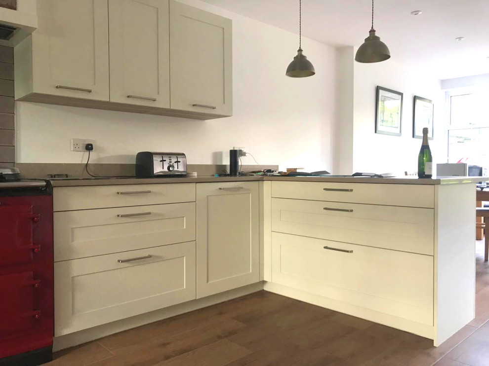 Inspiration for a large classic u-shaped open plan kitchen in Surrey with a submerged sink, shaker cabinets, grey cabinets, quartz worktops, grey splashback, ceramic splashback, stainless steel appliances, laminate floors, a breakfast bar, brown floors and brown worktops.