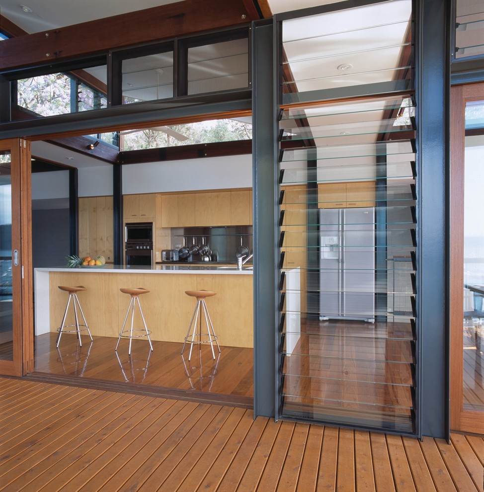 Foto di una cucina costiera con ante in legno chiaro, elettrodomestici in acciaio inossidabile e pavimento in legno massello medio