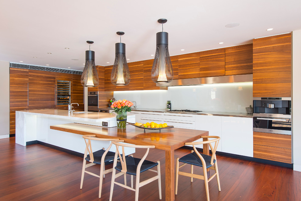 Moderne Küche mit Waschbecken, flächenbündigen Schrankfronten, hellbraunen Holzschränken, Küchenrückwand in Weiß, Glasrückwand, Küchengeräten aus Edelstahl, braunem Holzboden und Kücheninsel in Sydney