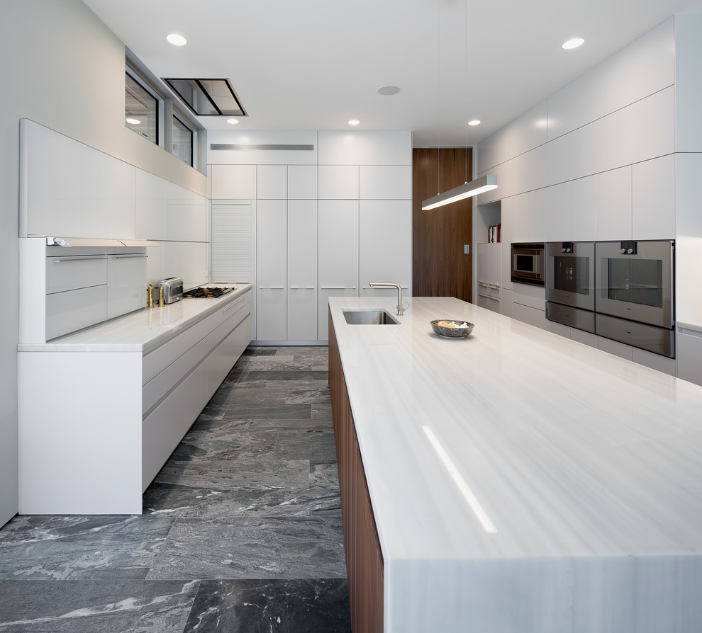 Inspiration for a large contemporary u-shaped kitchen/diner in Boston with a submerged sink, flat-panel cabinets, white cabinets, engineered stone countertops, white appliances, slate flooring, an island and grey floors.