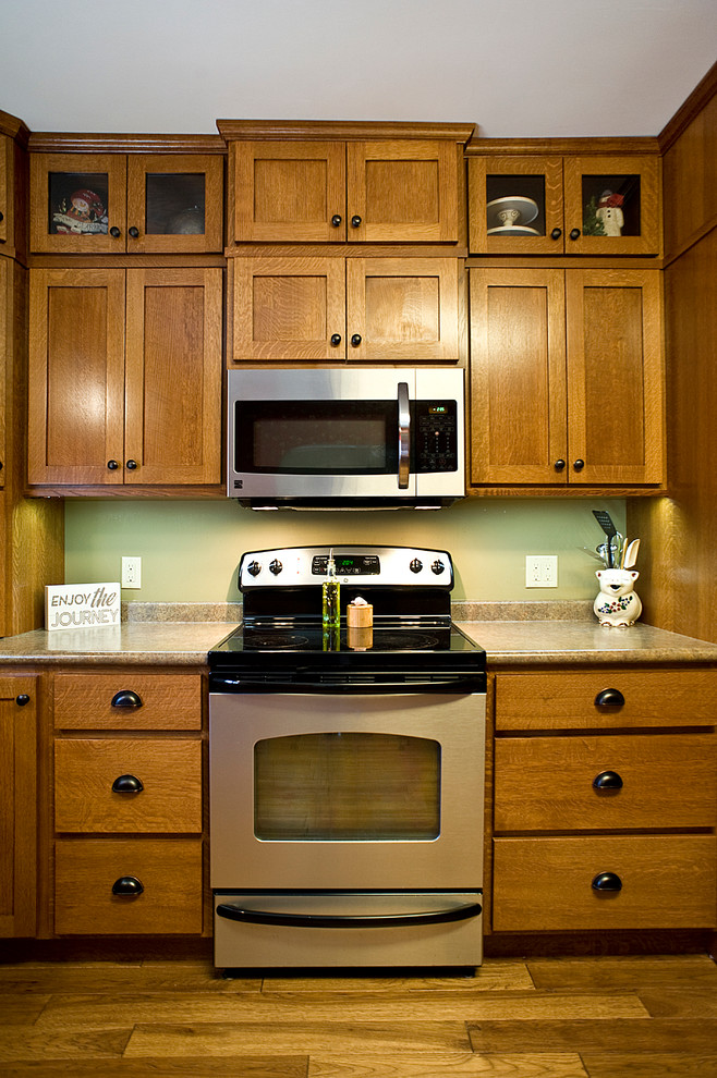 Bild på ett mellanstort amerikanskt kök, med en undermonterad diskho, skåp i shakerstil, skåp i mellenmörkt trä, laminatbänkskiva, grönt stänkskydd, rostfria vitvaror, mellanmörkt trägolv och brunt golv